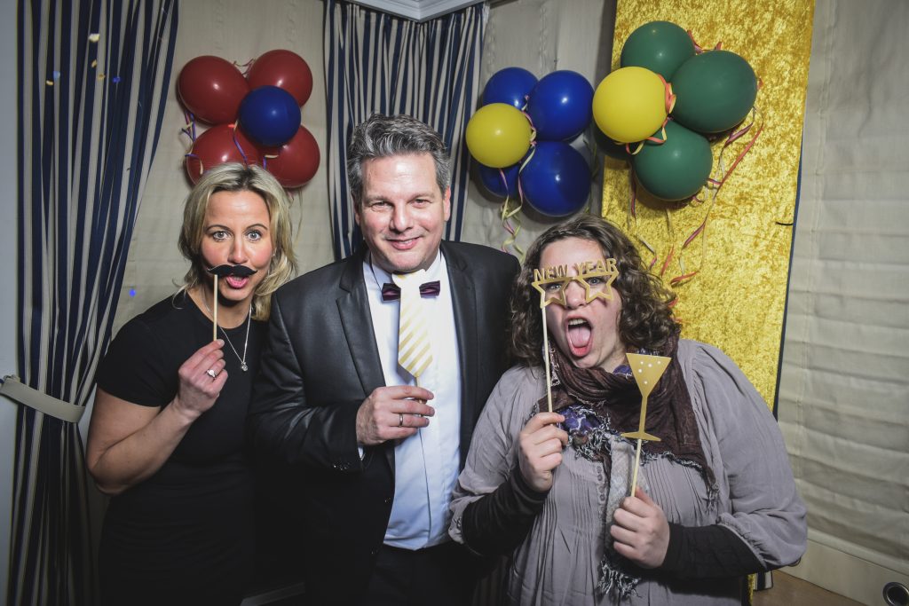 Partygäste mit Fun-Artikeln vor der Fotobox beim Geburtstag