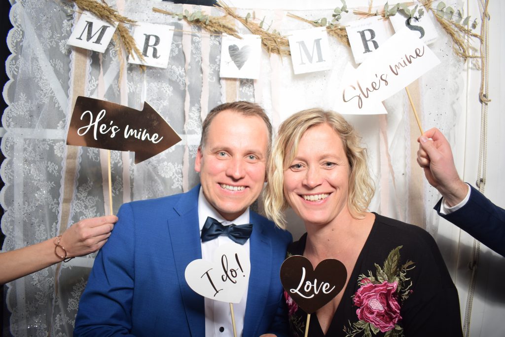 Brautpaar mit Schildern vor der Fotobox auf einer Hochzeit in Rostock