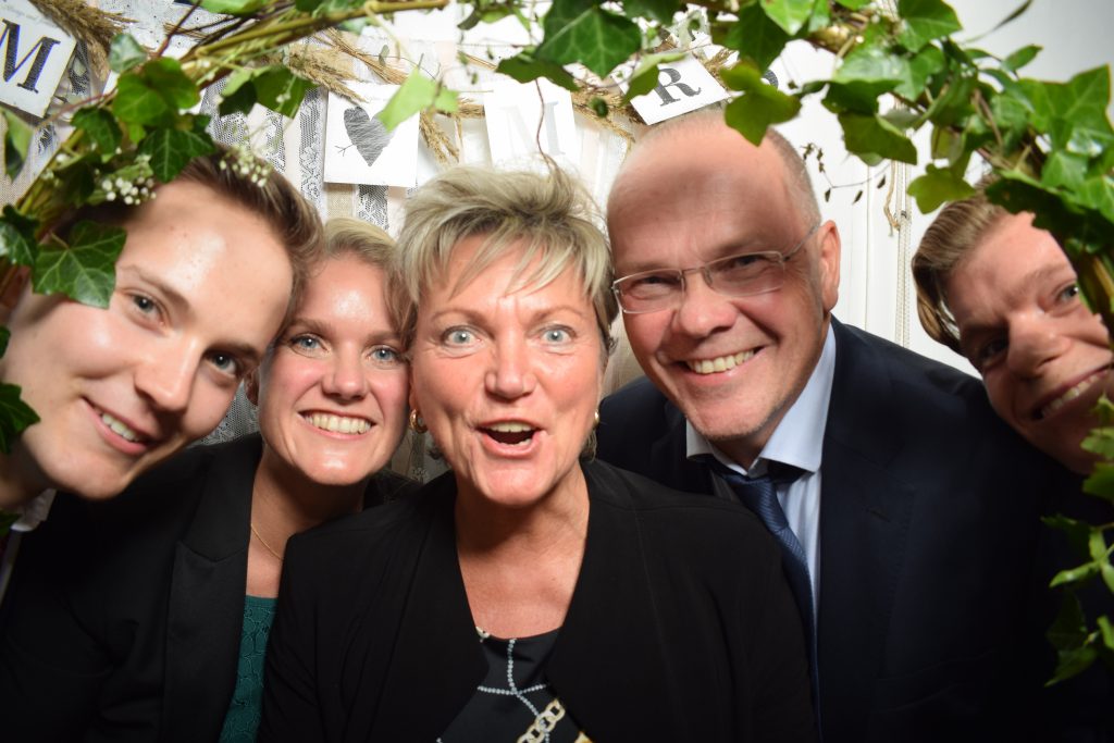 Gäste einer Firmenfeier lachen gemeinsam in die Fotobox