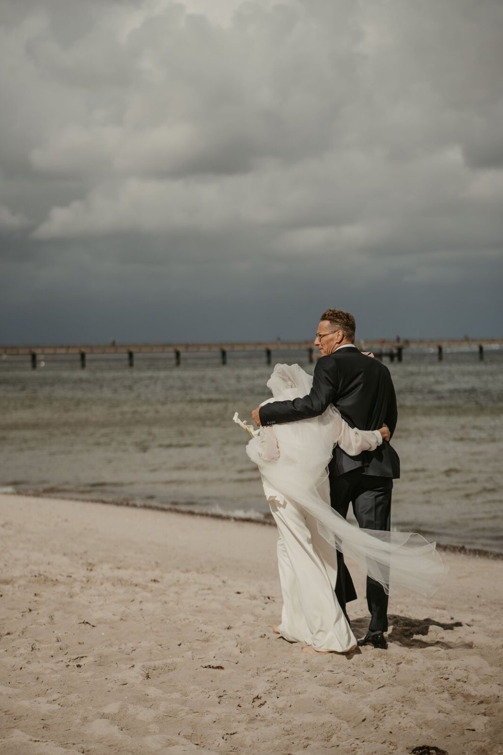 Brautpaar im Wind am Strand von Binz, im Hintergrund die Seebrücke