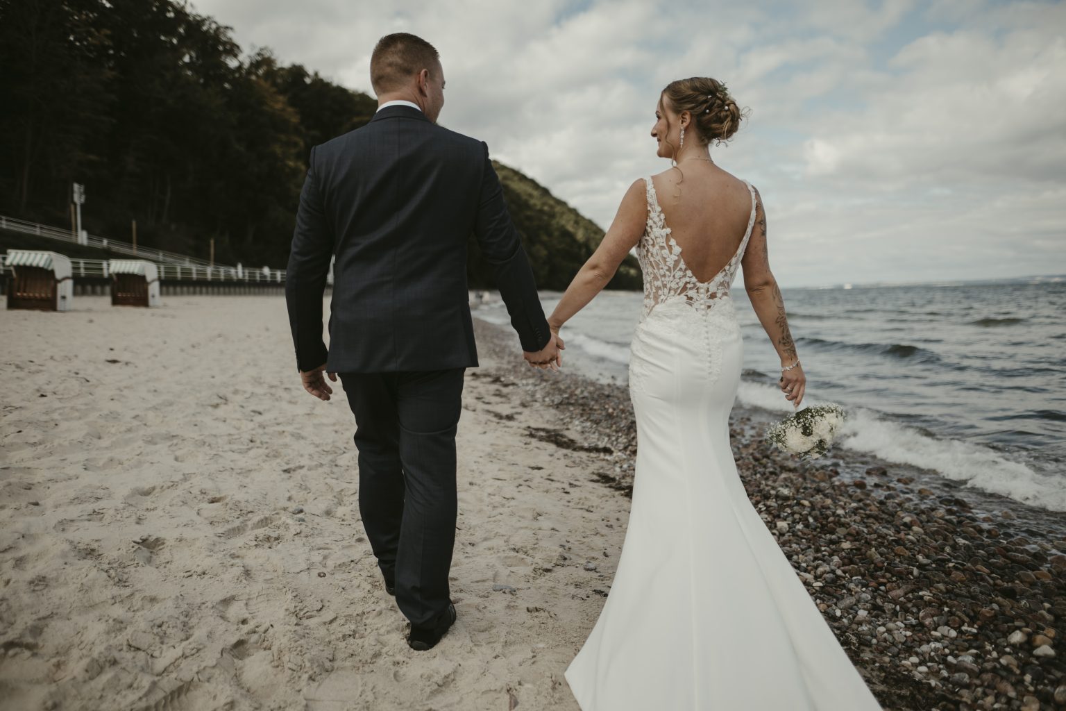 Brautpaar geht Hand in Hand am Strand von Sellin Richtung Steilküste
