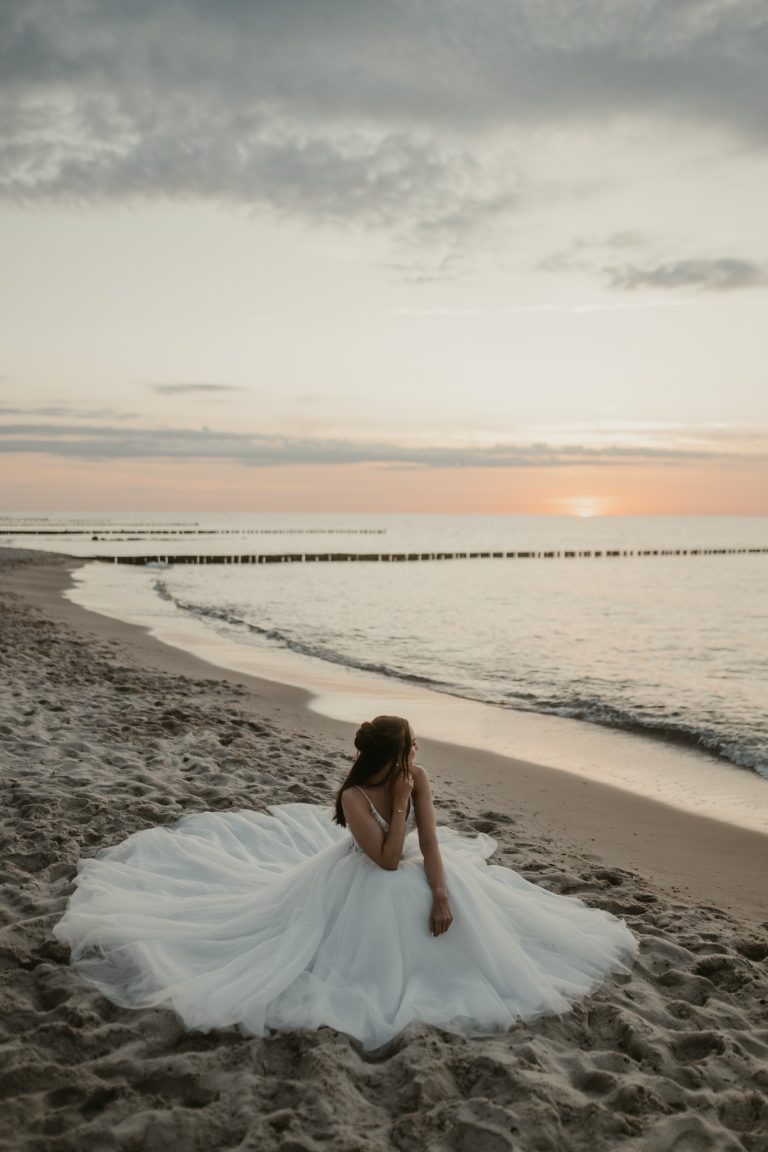 Braut im ausgebreiteten Kleid am Ostseestrand
