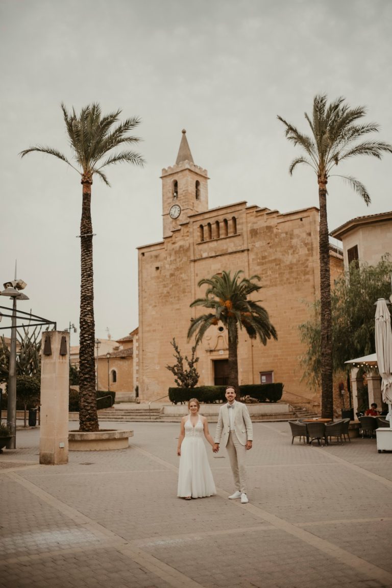 Brautpaar auf einem Platz mit Palmen und Kirche bei Manacor