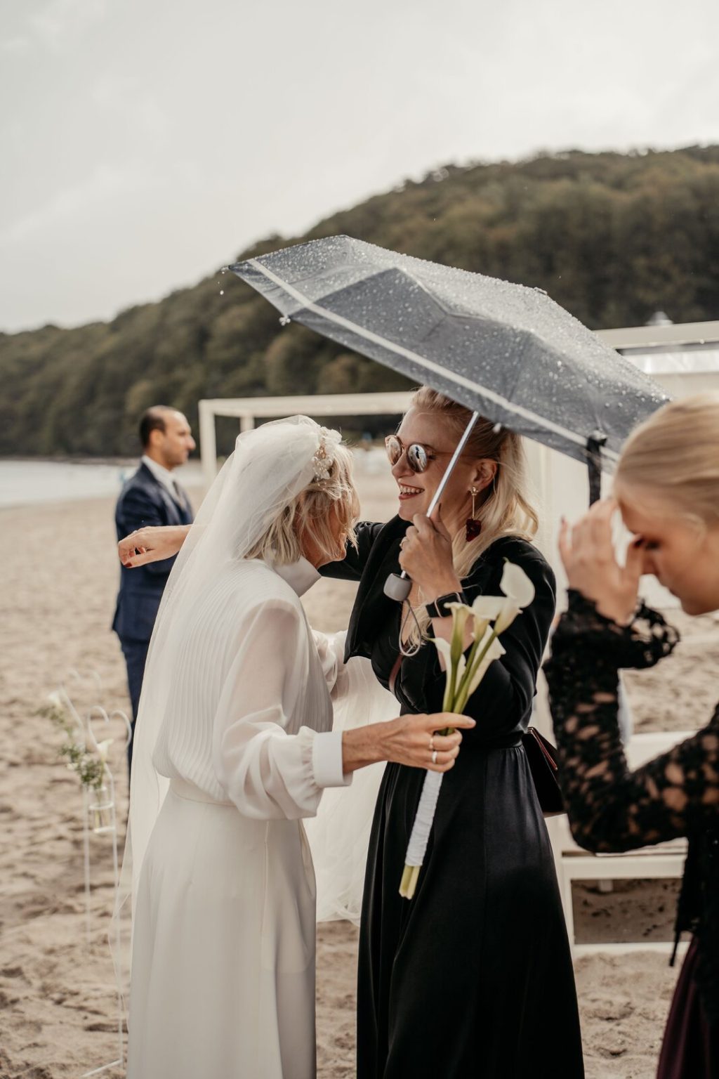 Braut unter Regenschirmen beim Sektempfang am Strand von Binz